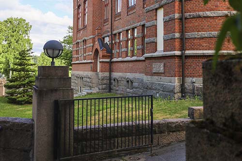 Vanha koulurakennus, jonka sisäänkäynnin portti on avoinna.